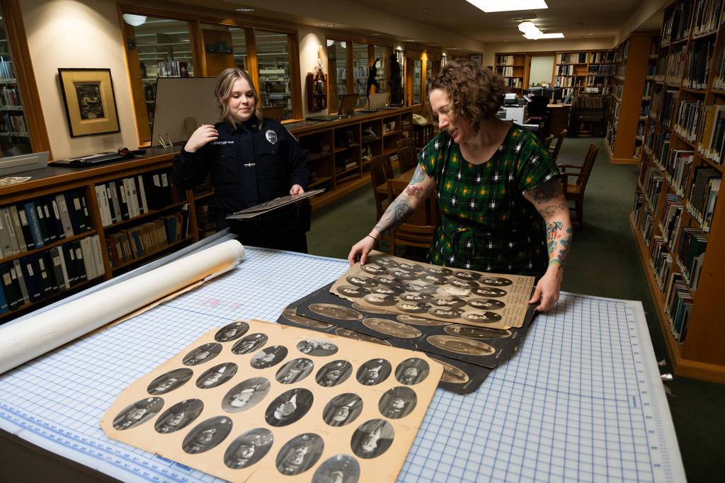 Will Geschke / The Herald 
Lisa Labovitch, right, pulls out archival photos of Everett police officers from the early 1900s in the Northwest Room of the Everett Public Library on Friday.