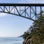 People walk across Deception Pass Bridge as a whale watcher boat passes underneath on Monday, March 2, 2026 in Anacortes, Washington. (Olivia Vanni / The Herald)