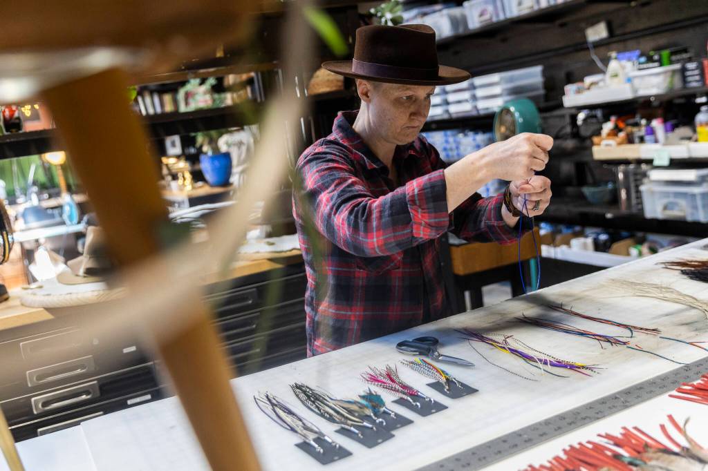 Jen Boede selects individual hand-dyed feathers for earrings at FauxyFurr Vintage + Handmade on Tuesday, June 2, 2026 in Arlington, Washington. (Olivia Vanni / The Herald)