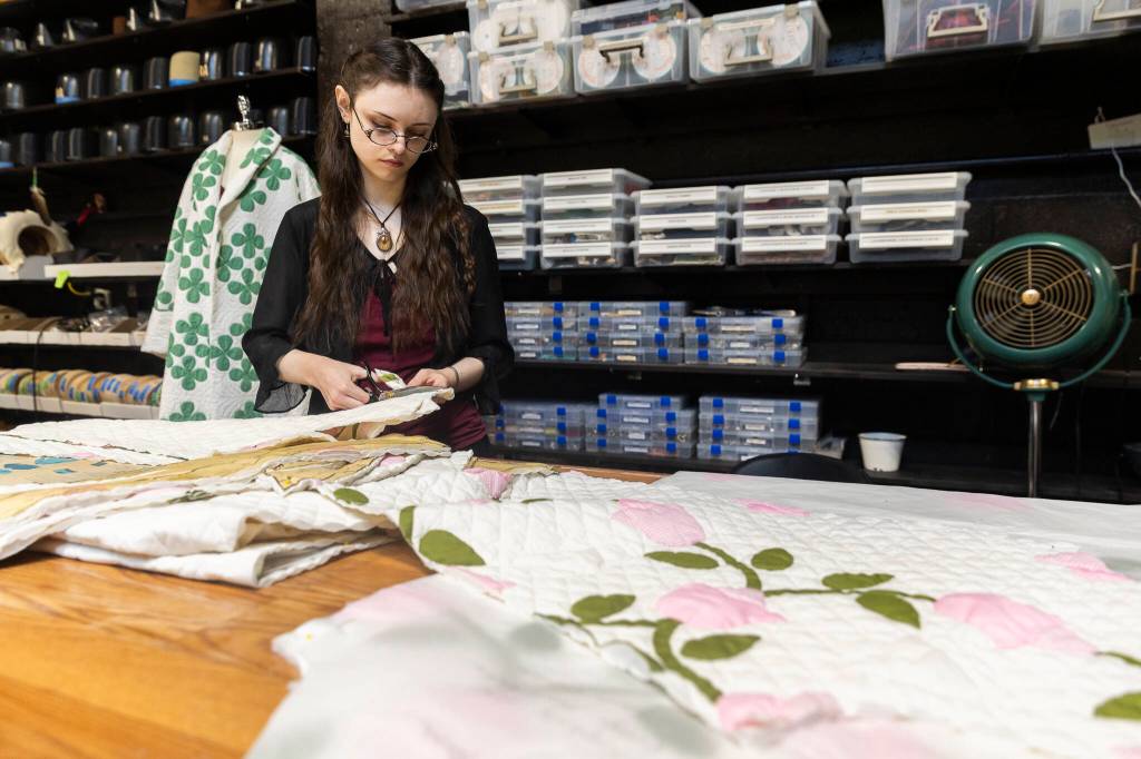 Matti Birdsong cuts a thrifted quilt to be made into a robe at FauxyFurr Vintage + Handmade on Tuesday, June 2, 2026 in Arlington, Washington. (Olivia Vanni / The Herald)