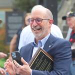 Edmonds Mayor Mike Rosen takes a photo while holding a plaque honoring Edmonds as the nations first community of service during a launch for Edmonds Serves on Saturday in Edmonds. (Michael Henneke / The Herald)