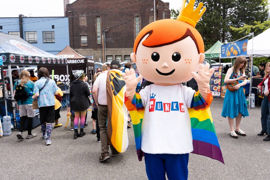 A Funko mascot stands with a Pride flag during the Everett Pride block party on Saturday, June 20, 2026, in Everett, Washington. (Will Geschke / The Herald)
