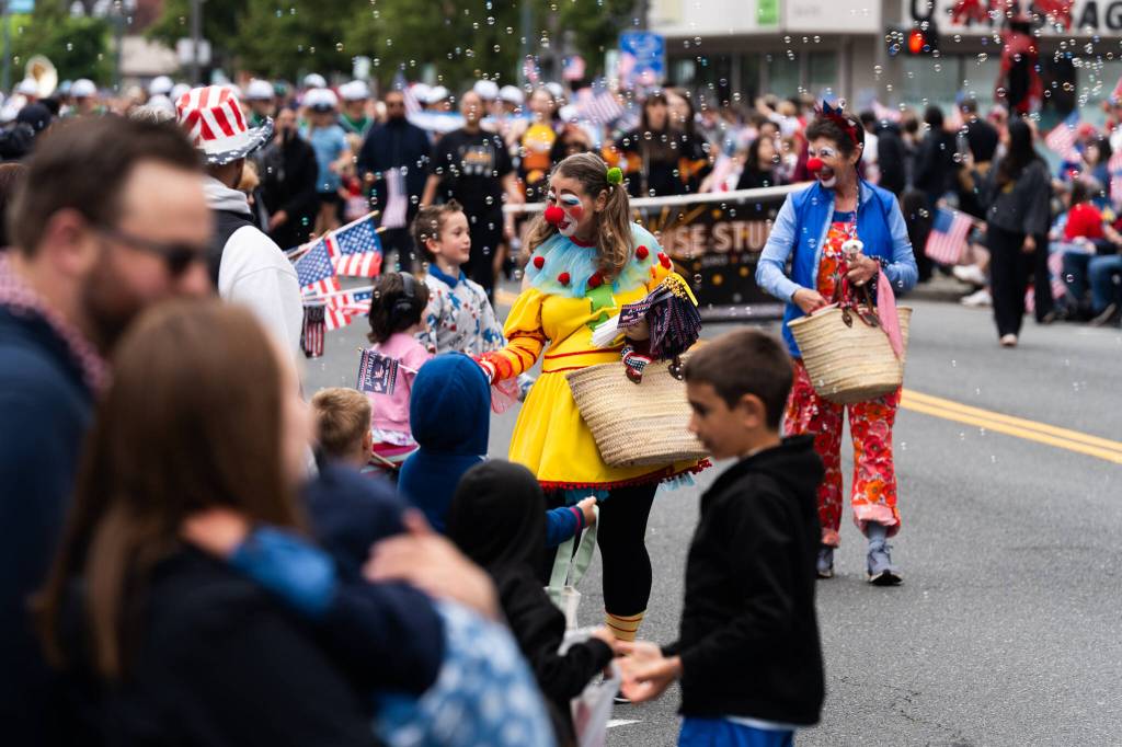 Representatives of the Bayside Neighborhood Association, dressed in clown outfits, pass out goodies to children along the Everett Independence Day parade route on Saturday, July 4, 2026 in Everett, Washington. (Will Geschke / The Herald)