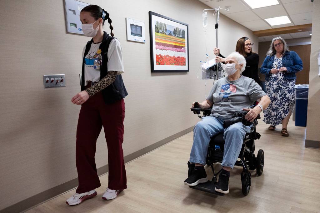 Infusion nurse Leinani Medellin and patient Debbie Goman make their way to Gomans infusion room at the infusion center at Providence Regional Medical Center Everett on Thursday, July 2, 2026 in Everett, Washington. (Olivia Vanni / The Herald)