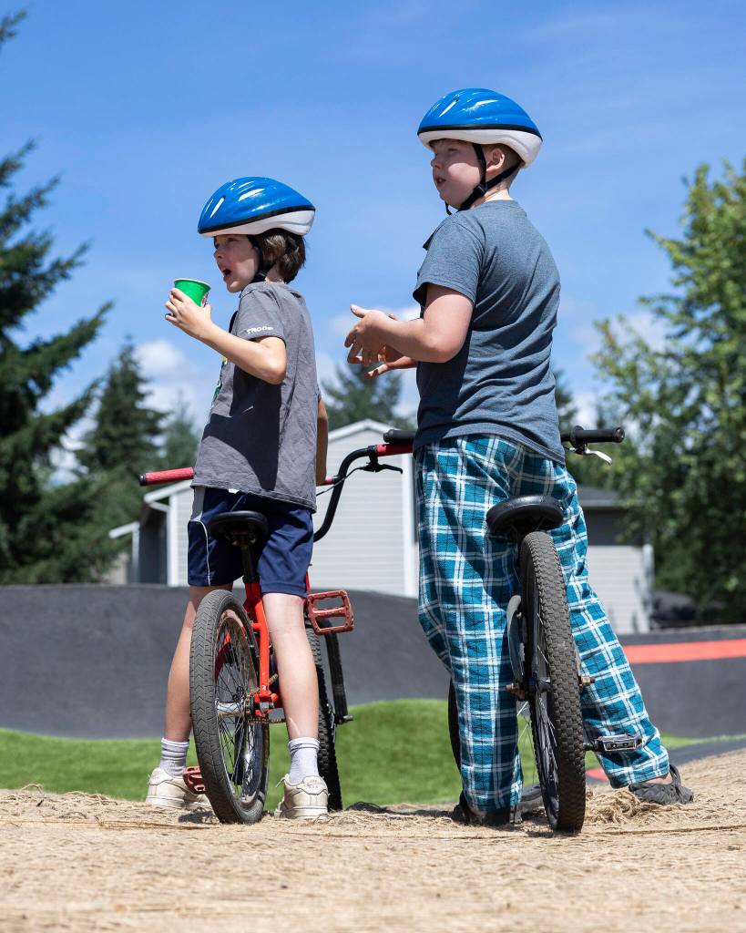 A pair of cyclists wait for the OK to use the pump track during the ribbon cutting at Jensen Park on Wednesday, July 29, 2026 in Arlington, Washington. (Olivia Vanni / The Herald)