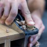 AJ Hansen trims the edges of a table leaf stand at the Bandpass Design workshop on July 28 in Edmonds, Washington. (Olivia Vanni / The Herald)