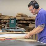 Chris Potter cuts a beveled edge for a table at the Bandpass Design shop on July 28 in Edmonds, Washington. (Olivia Vanni / The Herald)