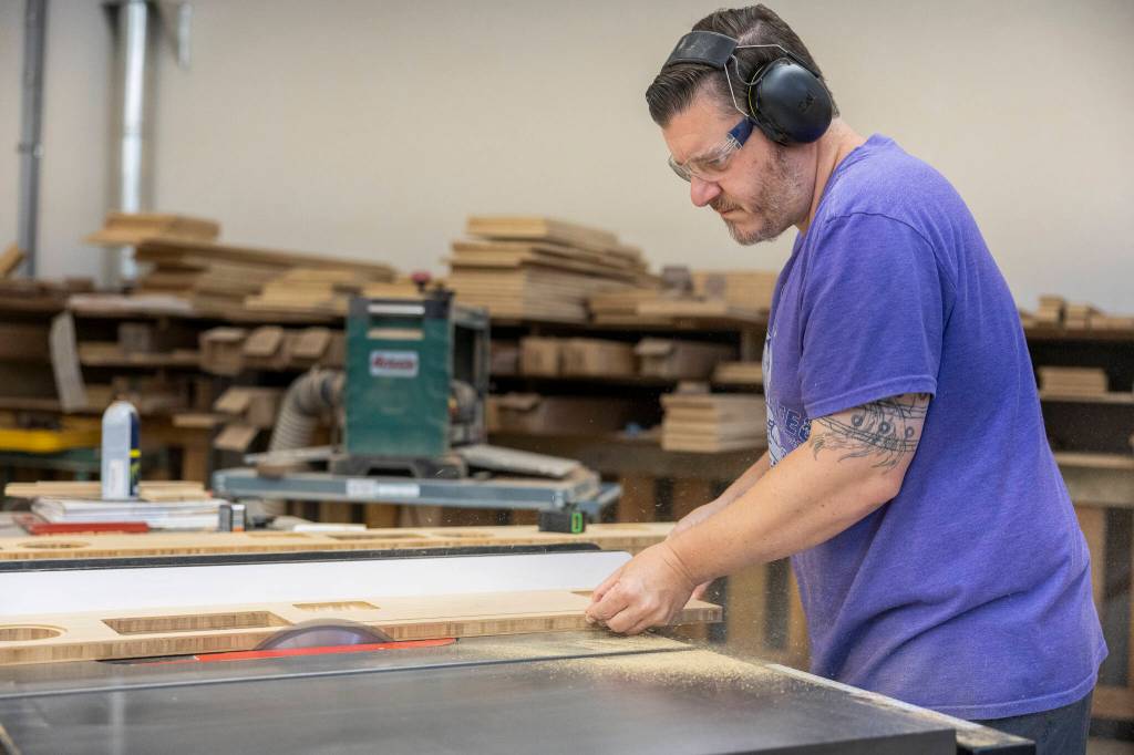Chris Potter cuts a beveled edge for a table at the Bandpass Design shop on July 28 in Edmonds, Washington. (Olivia Vanni / The Herald)
