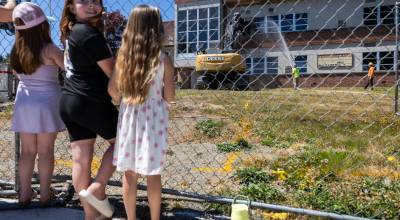 People gather to watch the start of demolition of Jackson Elementary School along Federal Avenue on Thursday, July 30, 2026 in Everett, Washington. (Olivia Vanni / The Herald)