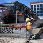 Construction works wrap danger tape around the Jackson Elementary School sign before the start of demolition on Thursday, July 30, 2026 in Everett, Washington. (Olivia Vanni / The Herald)