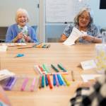 Kathy Hoppenrath and Judy Deeter chat while cutting out their dog coloring art during Old Friends Club at the Lynnwood Neighborhood Center on Wednesday, Aug. 12, 2026 in Lynnwood, Washington. (Olivia Vanni / The Herald)